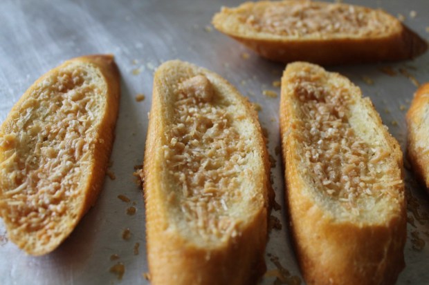 Slice a baguette on the diagonal. Generously brush each side with olive oil and top with shredded parmesan cheese. Place into a preheated 350 degree oven and bake for 25 minutes or until golden in color.